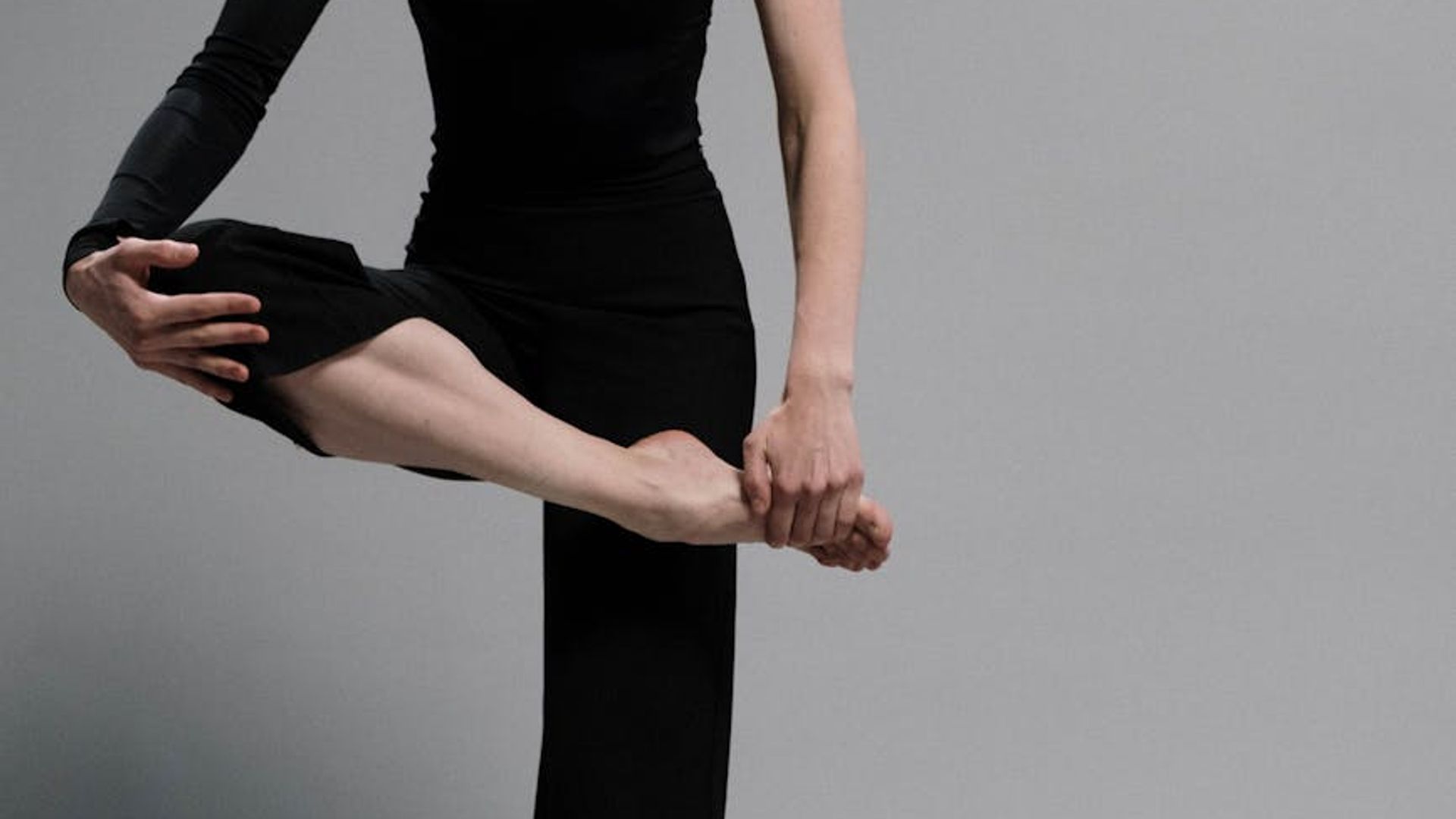 A serene woman in a focused yoga posture against a dark, calm background.