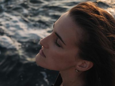 Side profile of a woman breathing deeply with eyes closed in a calm setting.